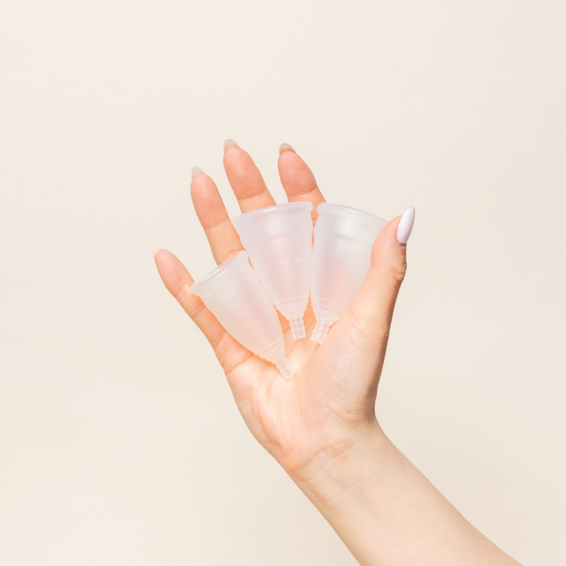 Hand holding Diva cups in all three sizes